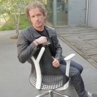 man-sits-chair-with-knife-his-hand